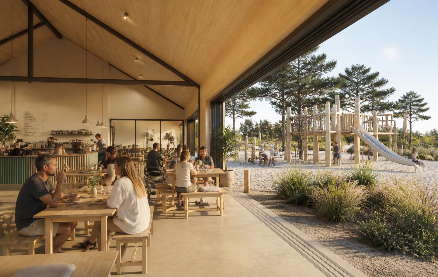 Parents enjoying coffee and lunch inside the barn while children play on the timber structure outside, with sliding doors open to the coast